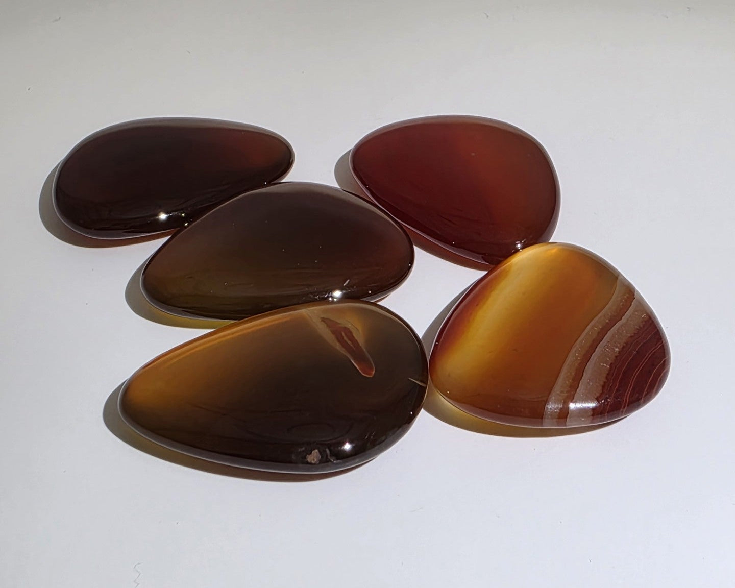 five carnelian palmstones flat on a white background