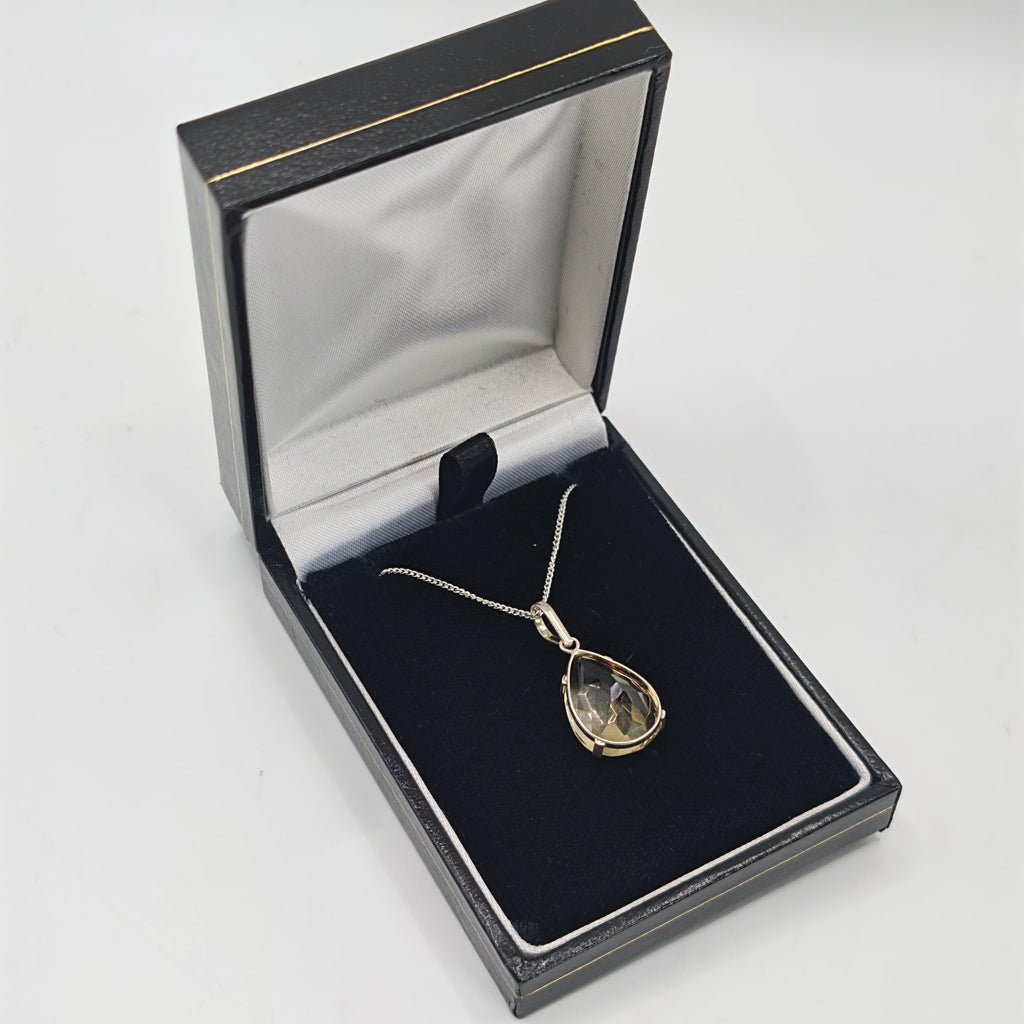 A silver sterling pendant necklace with a teardrop-shaped citrine set on a delicate chain, displayed inside an open black jewelry box with a black velvet insert.