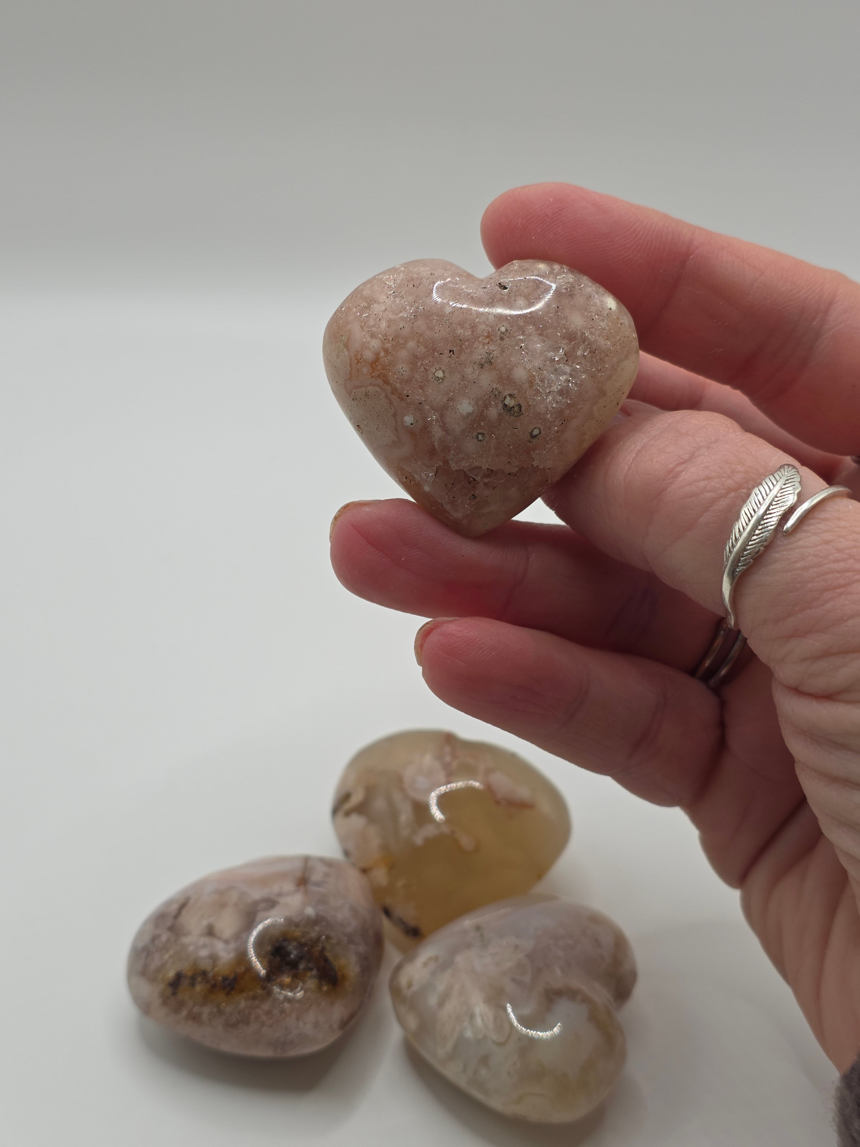 Hand holding a small stone with three more stones on a light gray background