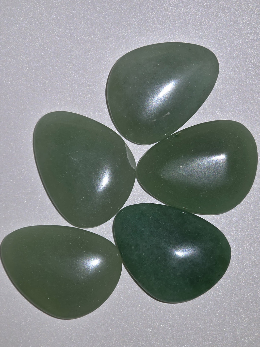 five green aventurine palms stones looking from above on a white background