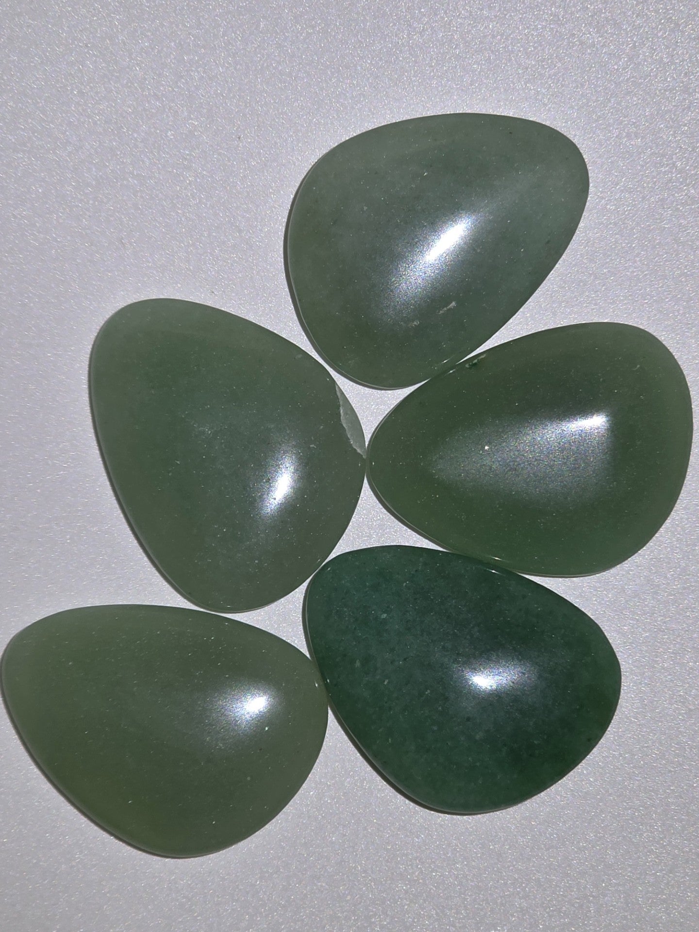 five green aventurine palms stones looking from above on a white background
