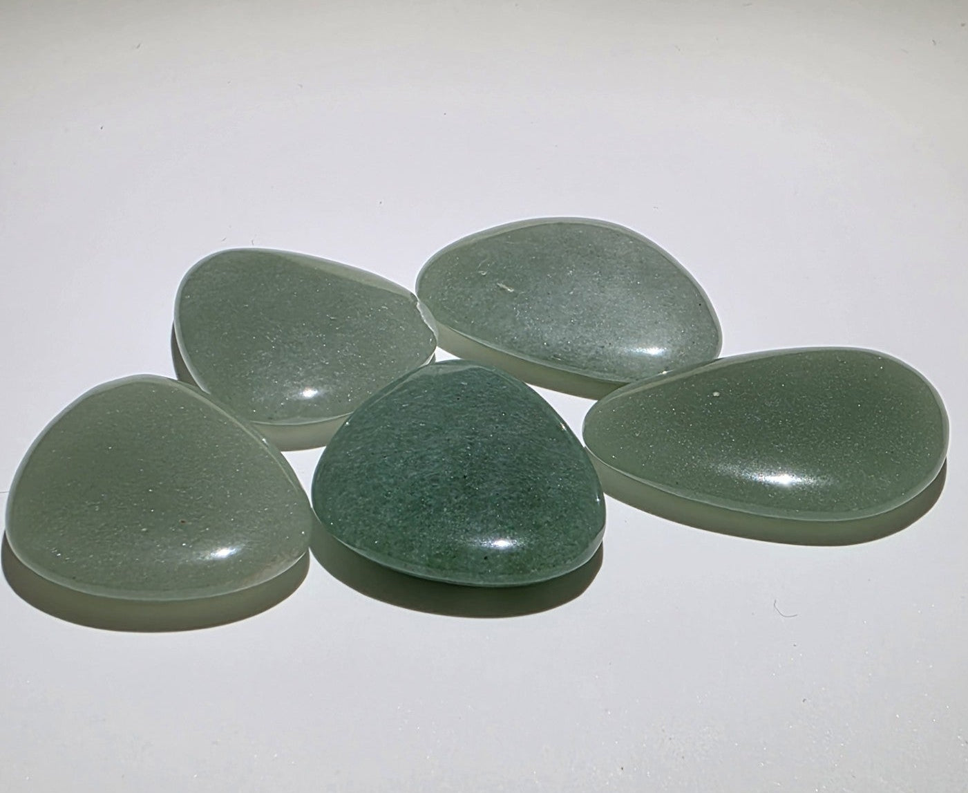 Five green avemturine stones on a white background