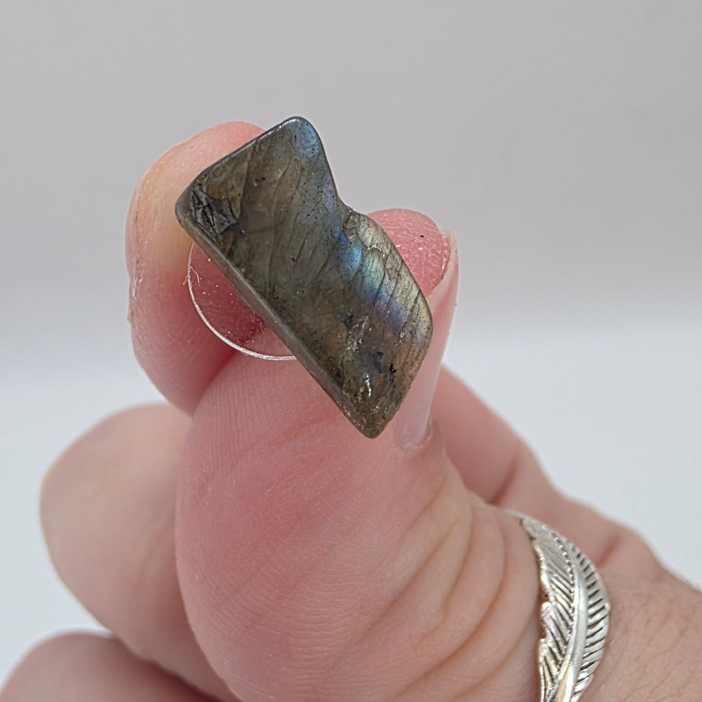 Hand holding a labradorite Stud earring  on a light background