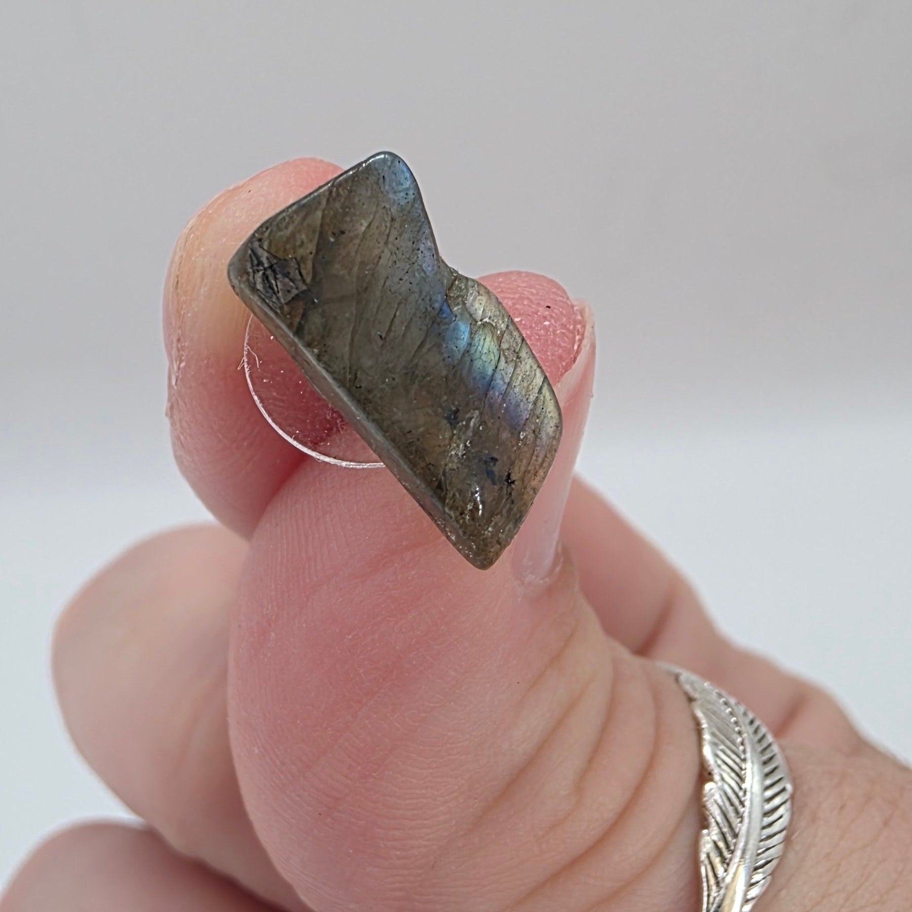 Hand holding a labradorite Stud earring  on a light background