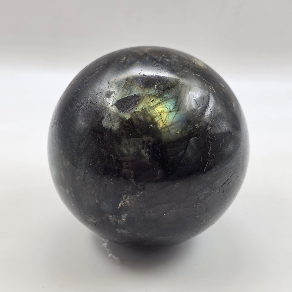 labradorite sphere with rainbow reflection on a white background