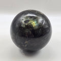 labradorite sphere with rainbow reflection on a white background
