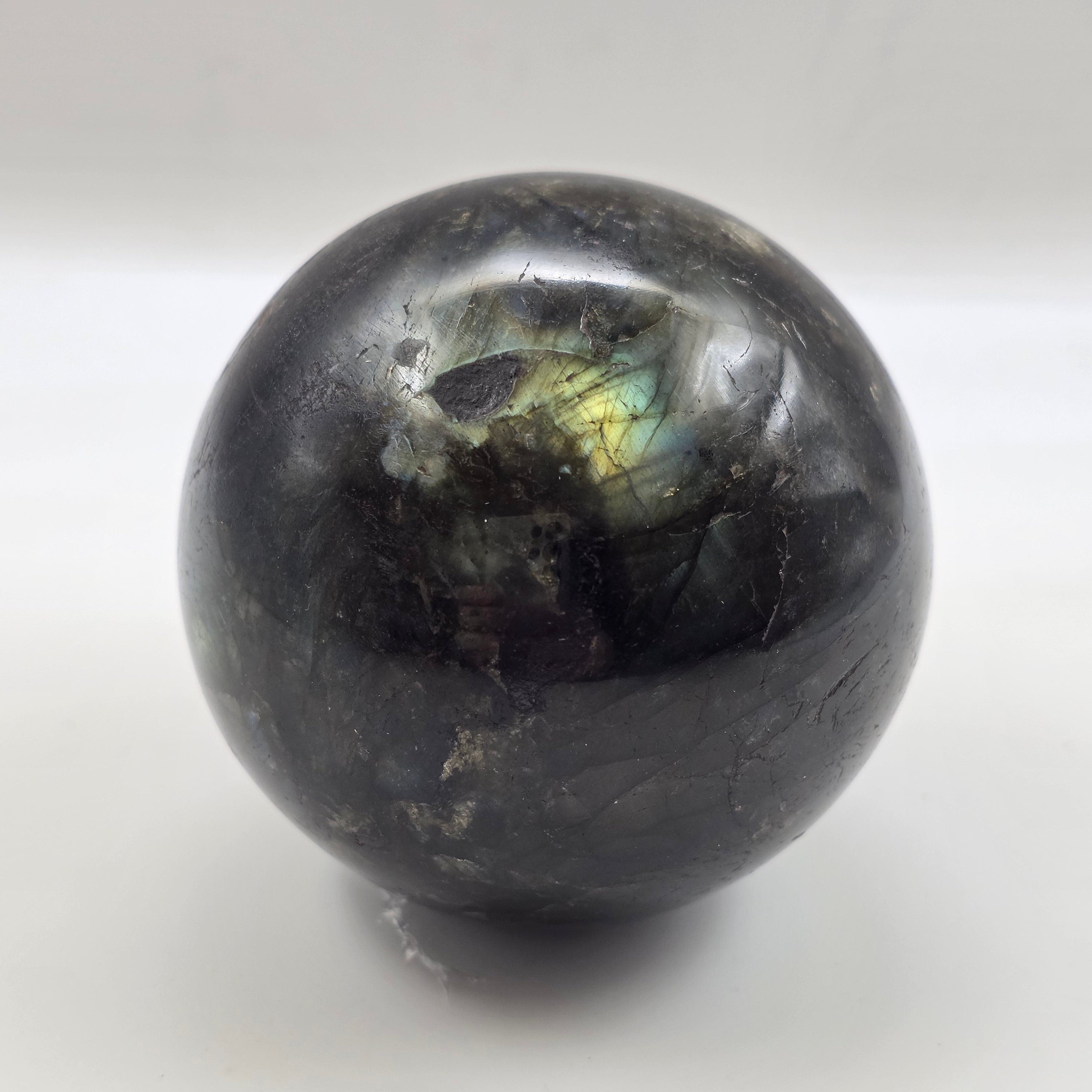 labradorite sphere with rainbow reflection on a white background