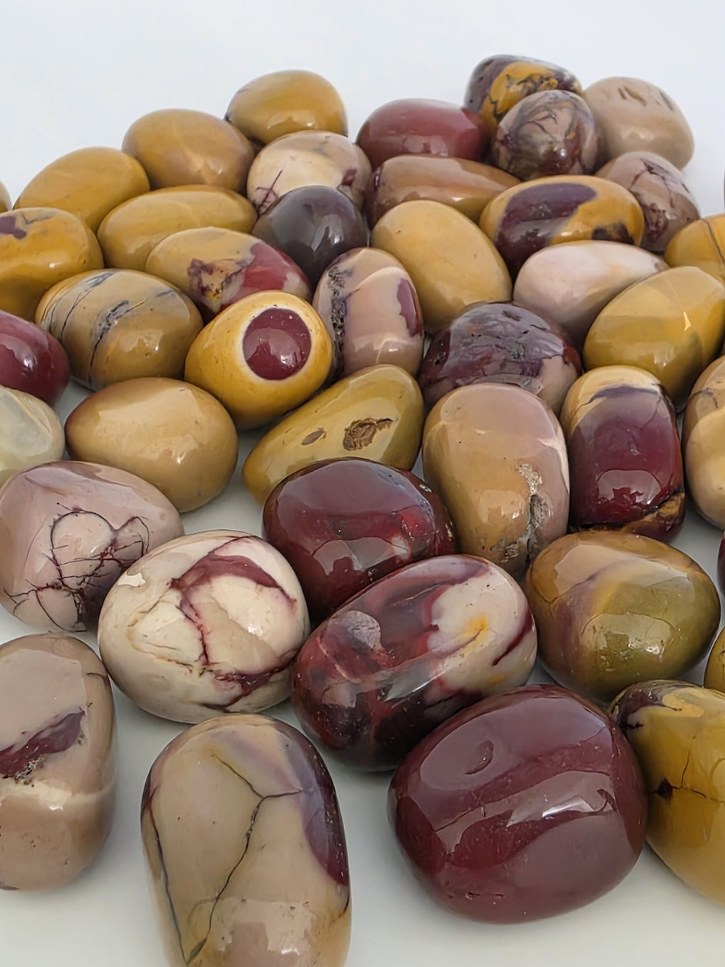 Collection of Mookaite stones in various colours on a white background