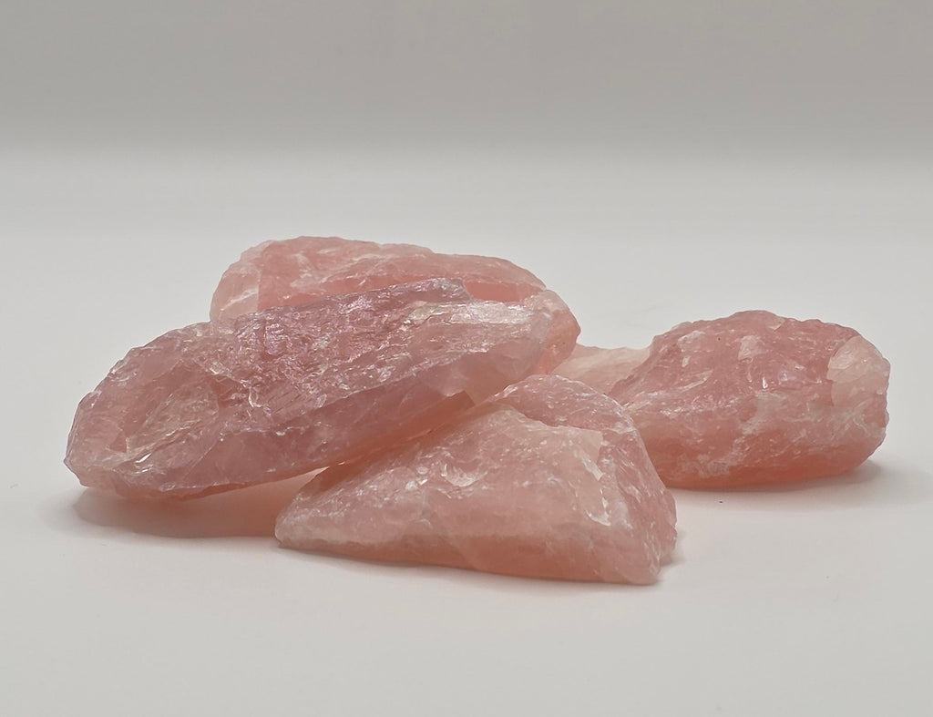 Four Raw rose quartz crystals laying down overlapping each other