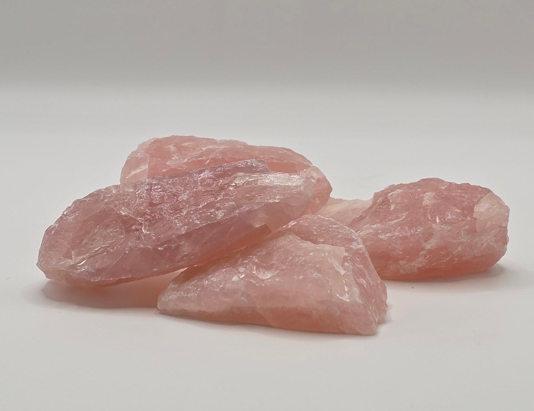 Four Raw rose quartz crystals laying down overlapping each other