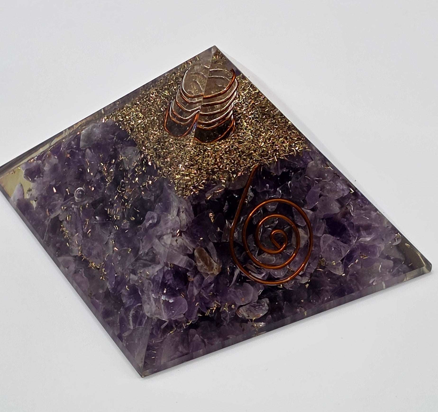 Angle of amethyst orgonite pyramid 60mm showing purple crystal chips, resin texture and quality