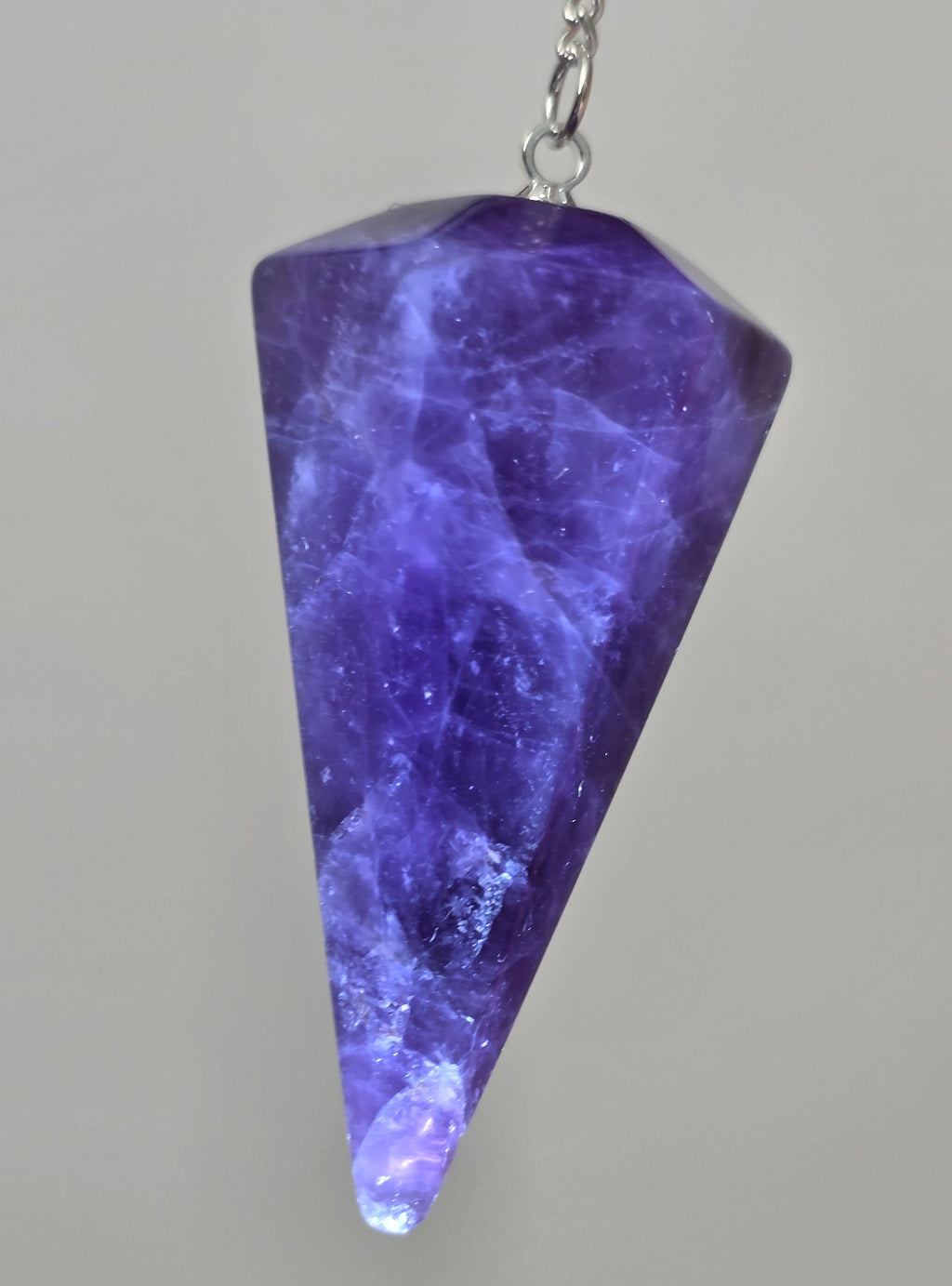 Close up of faceted amethyst crystal point showing deep purple colour and natural clarity