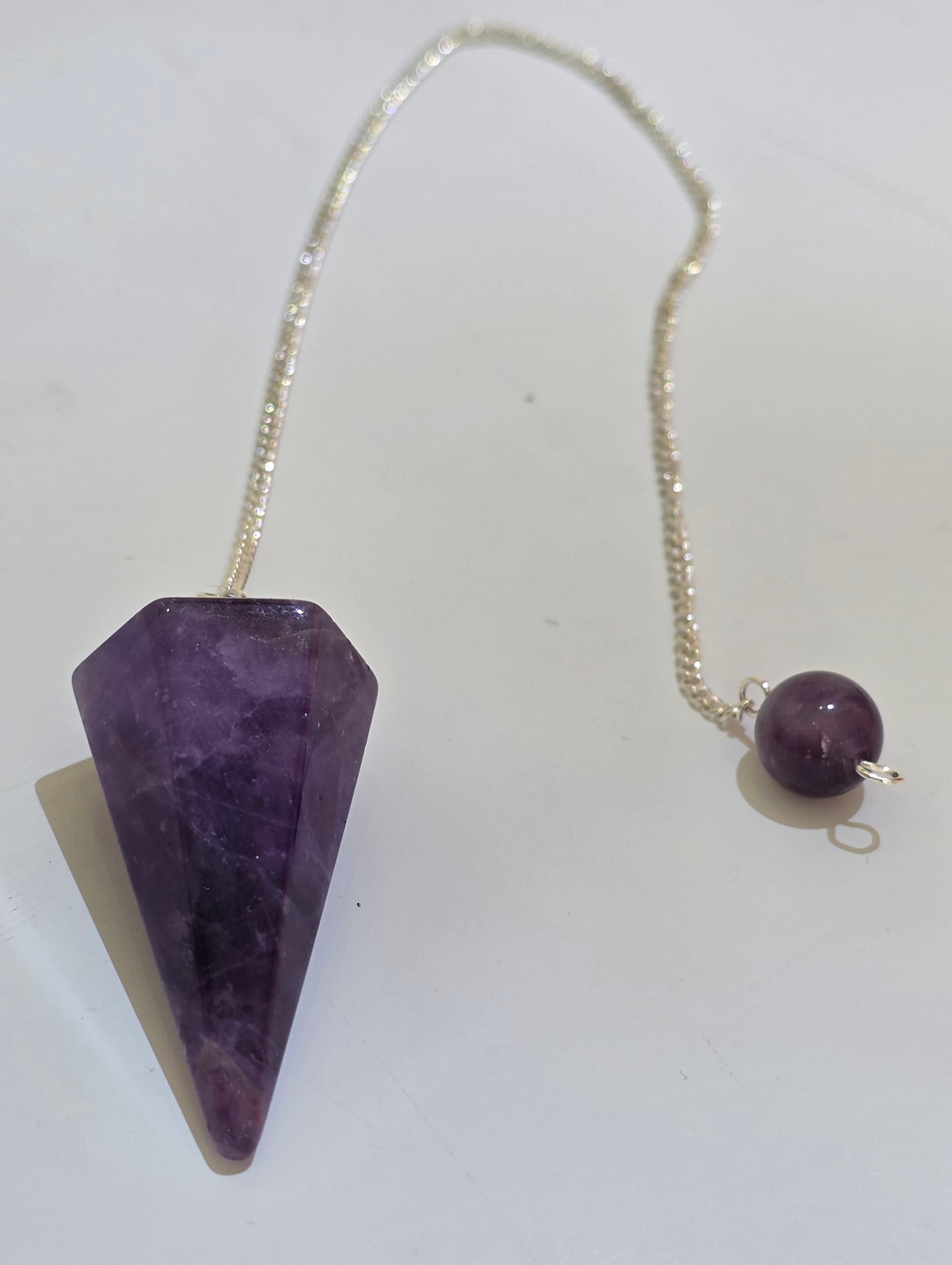 Amethyst faceted pendulum with silver plated chain on white background