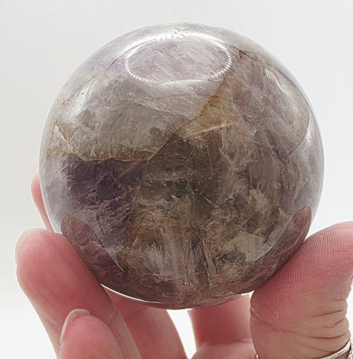 Amethyst sphere held in hand showing approximate 5-8cm size