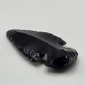 Hand-shaped black obsidian arrow head on white background – natural volcanic glass from Mexico, 3-5cm long, glossy black