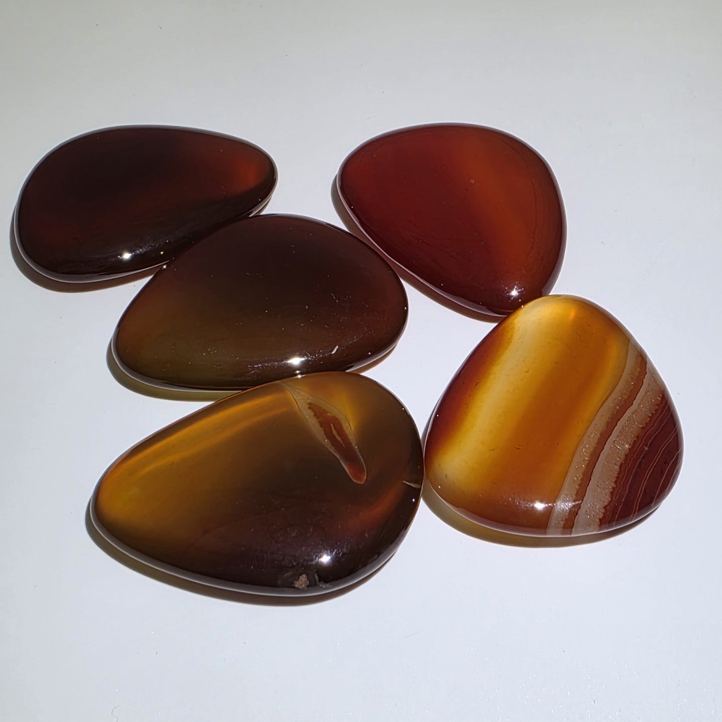 Five Carnelian palm stones on a white background