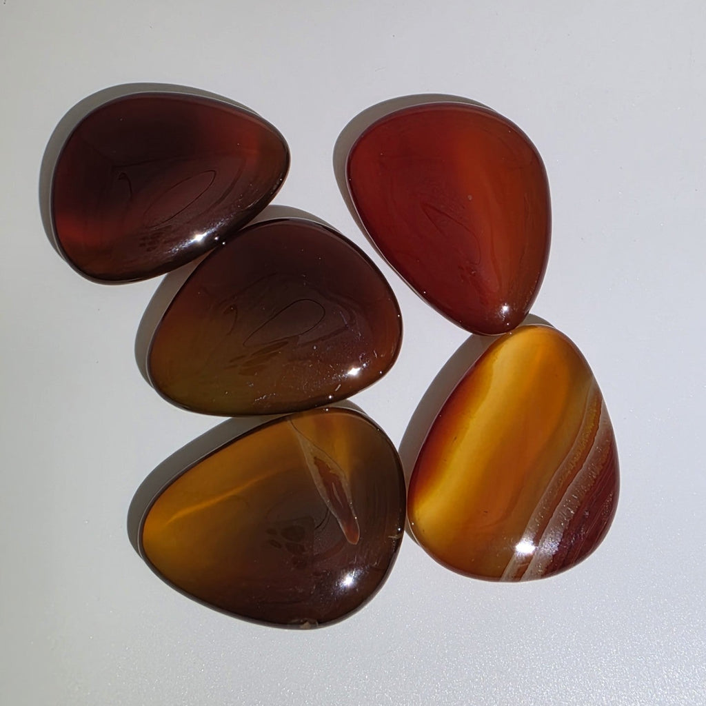 five carnelian palm stones birdseye view, on a white background