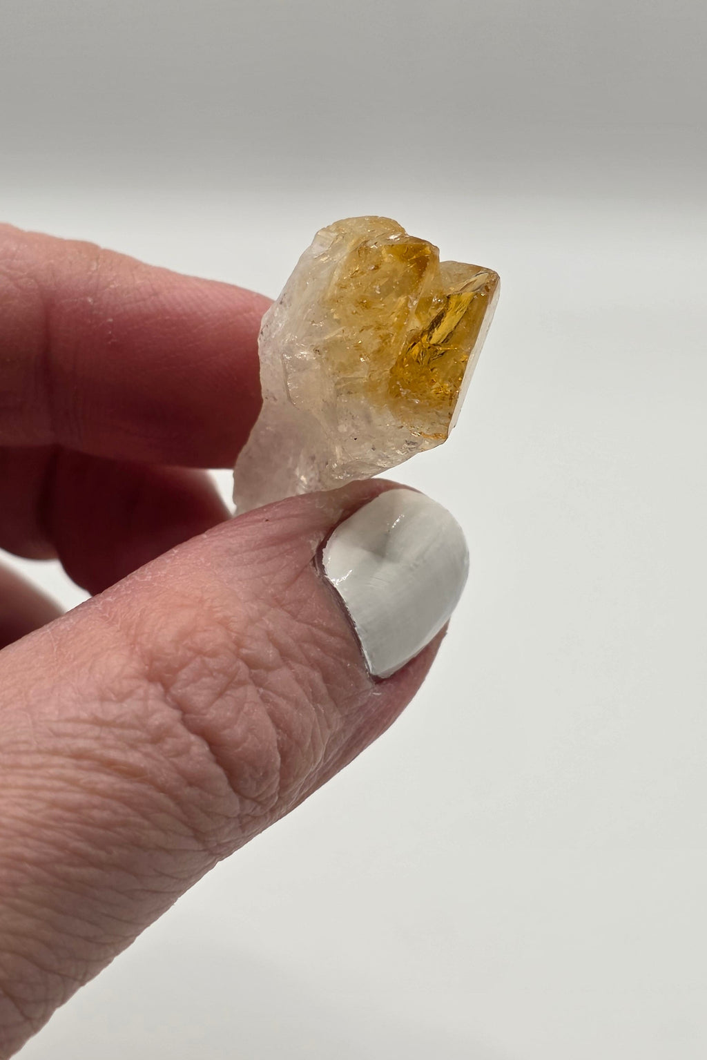 Natural citrine point held in a person's finger and thumb showing actual size – golden yellow Brazilian crystal tooth 2 to 3.5cm for manifestation