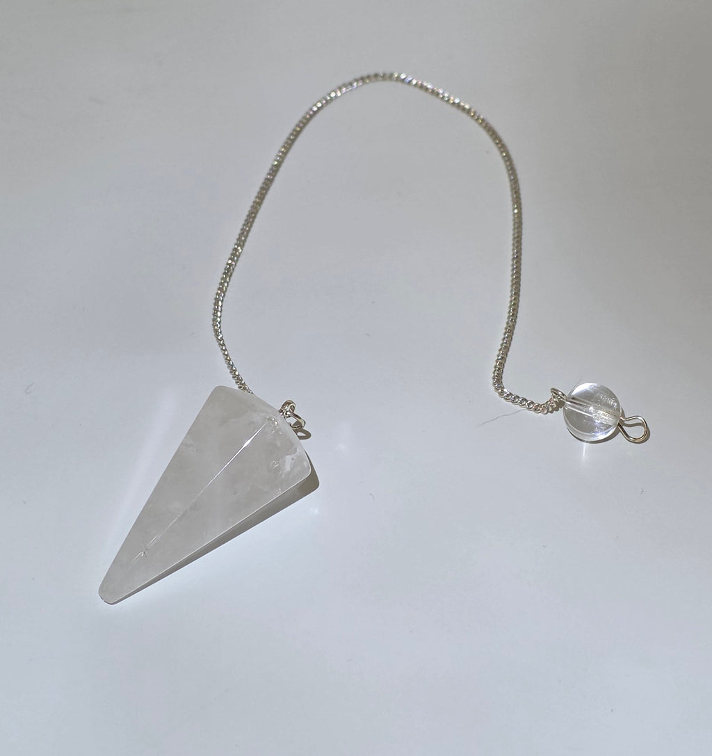 Clear quartz faceted pendulum with silver plated chain hanging on white background