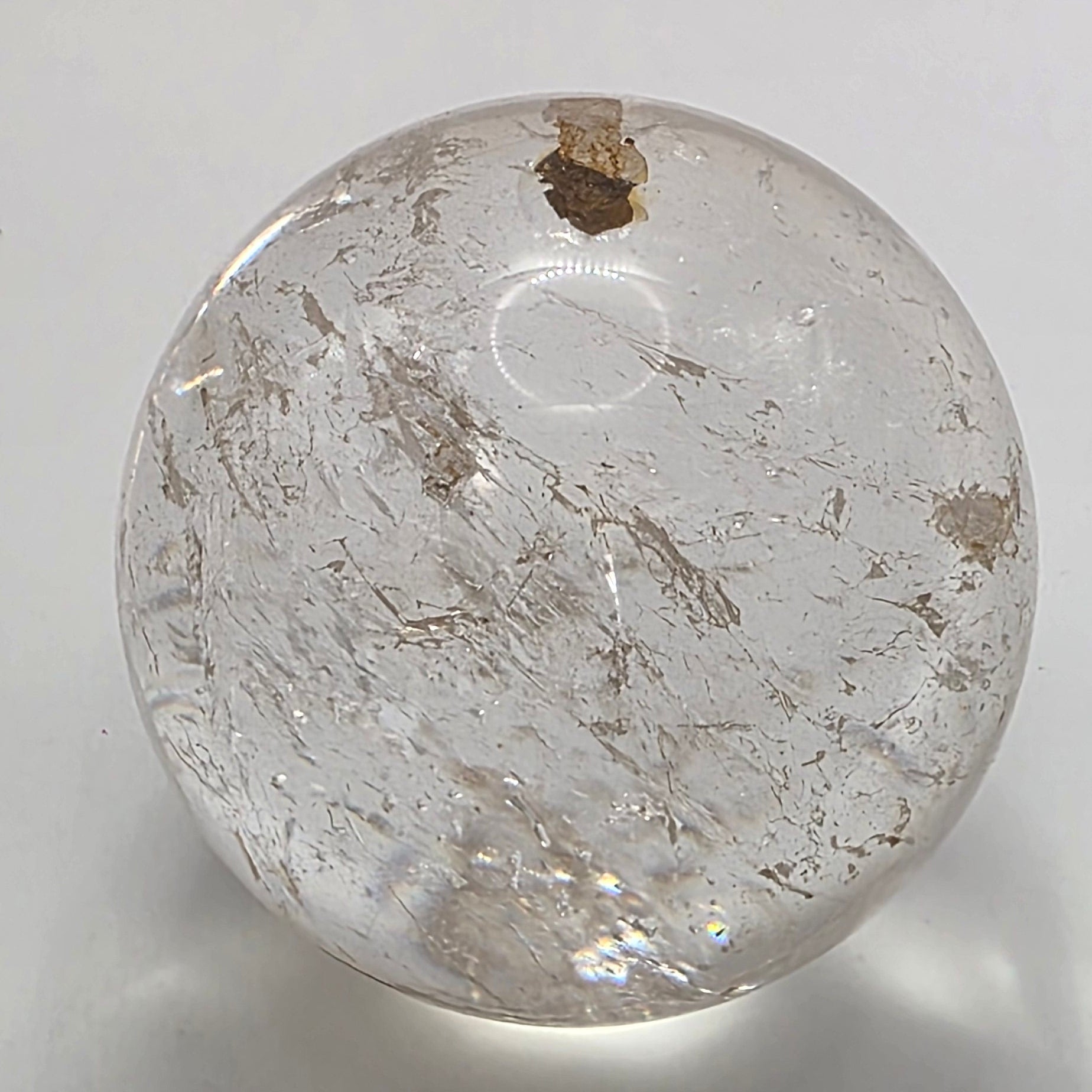 Polished 3.5cm clear quartz crystal sphere on white background