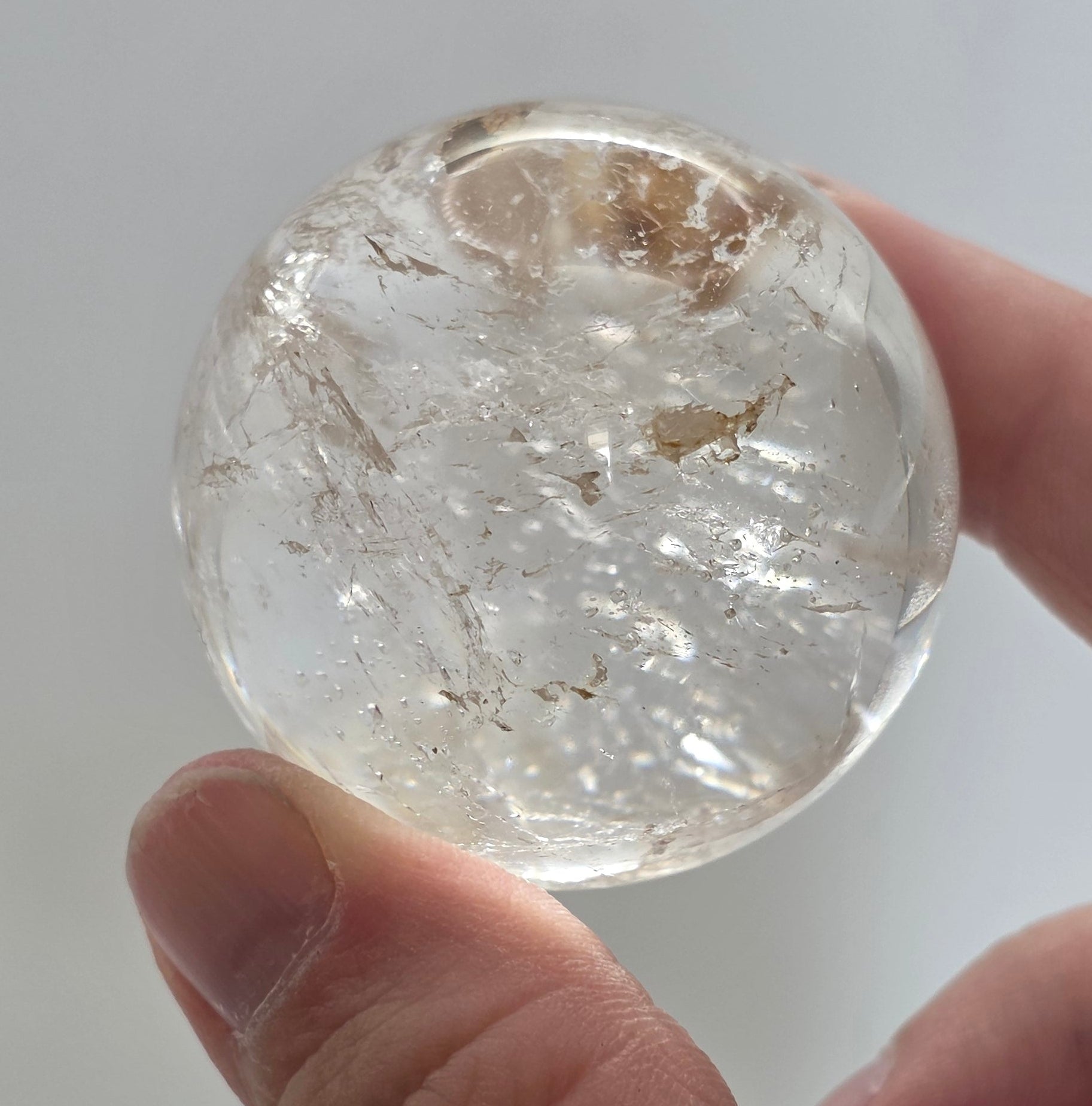 3.5cm clear quartz sphere held in hand showing size
