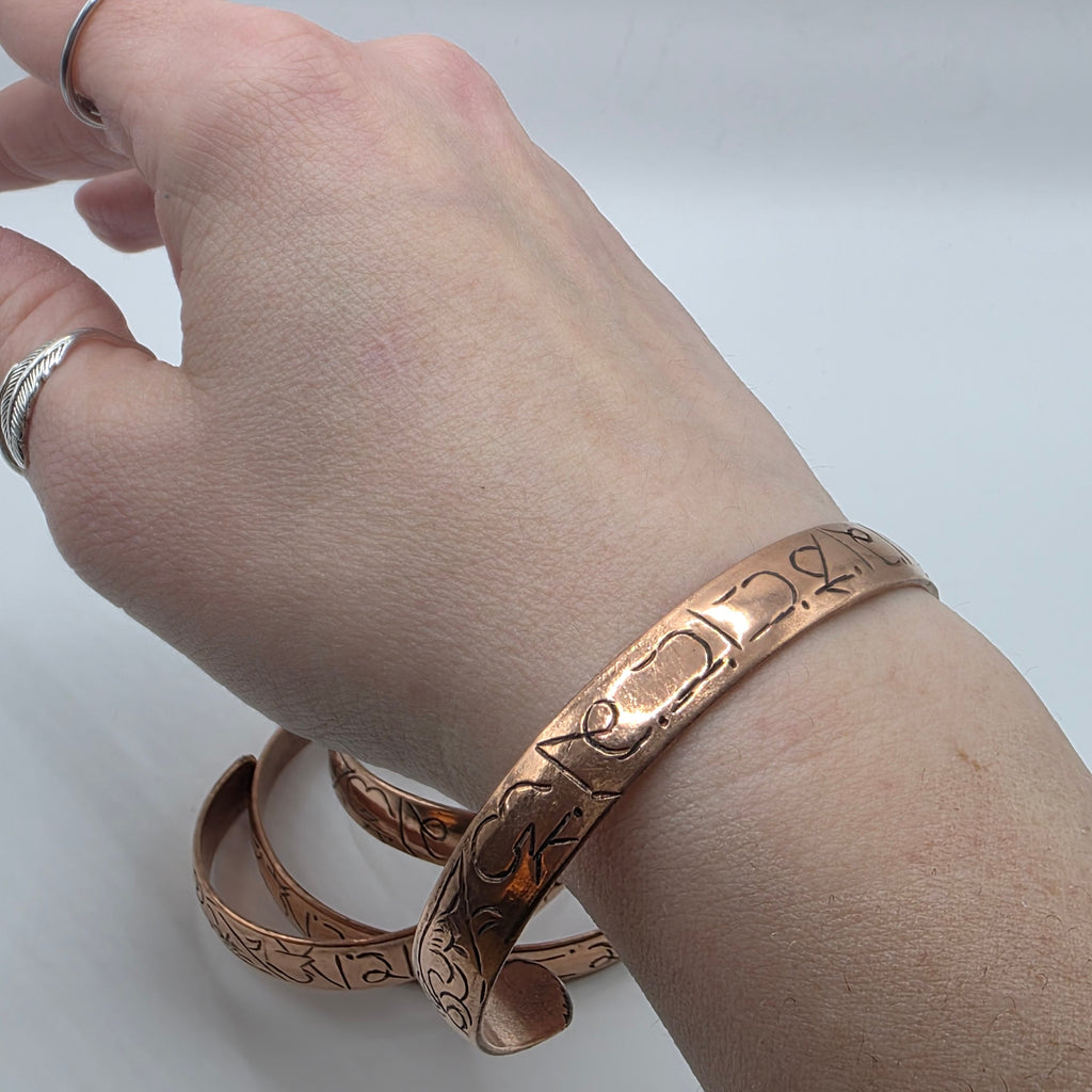 Adjustable copper cuff with buddhist mantra worn on a wrist – om mani padme hum etched copper bracelet