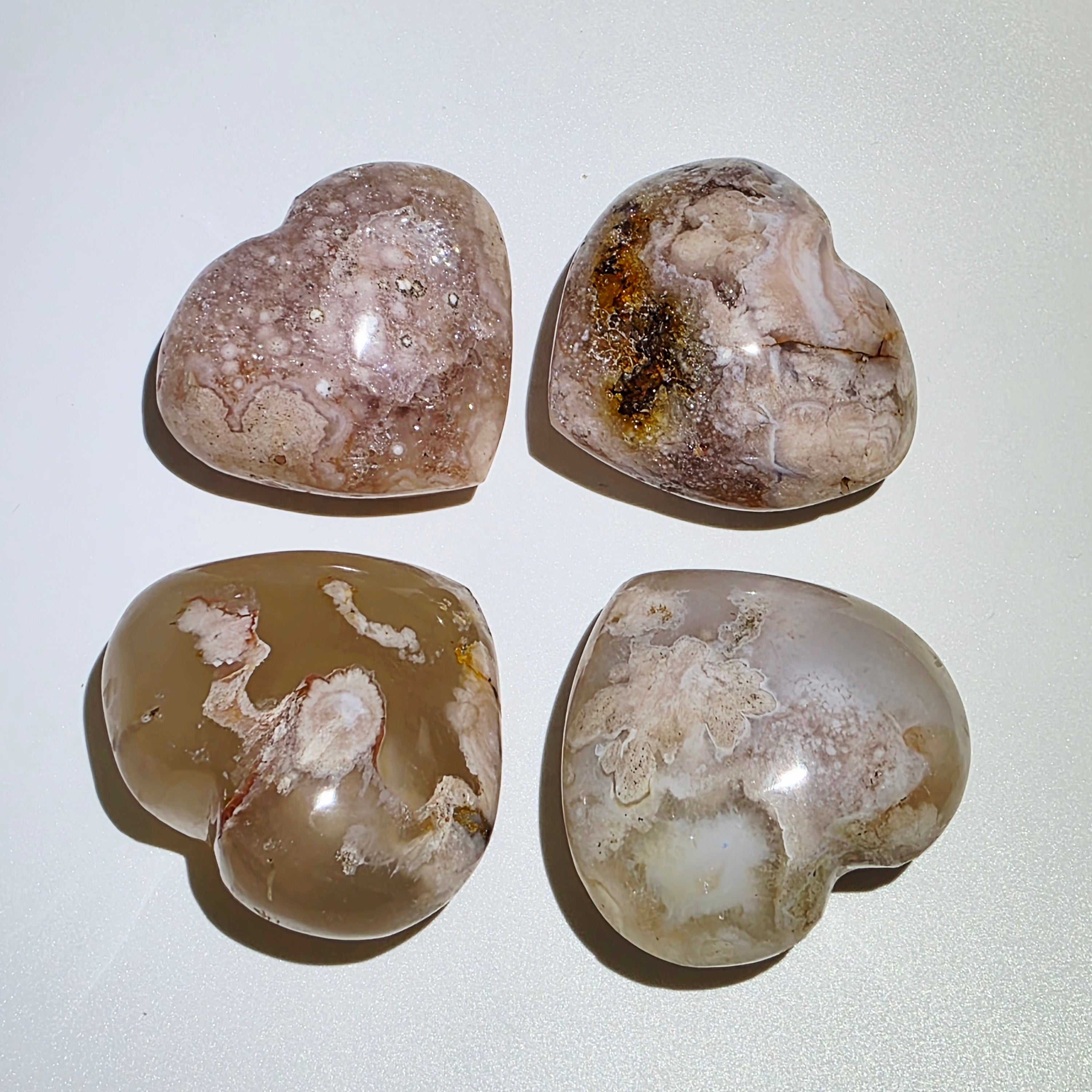 Four heart-shaped stones with marbled patterns on a white background