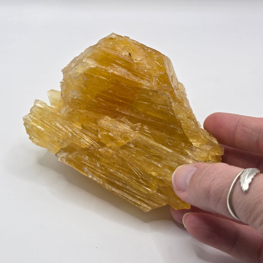 Golden calcite 470g held in a person's hand – natural raw crystal for energy cleansing and prosperity