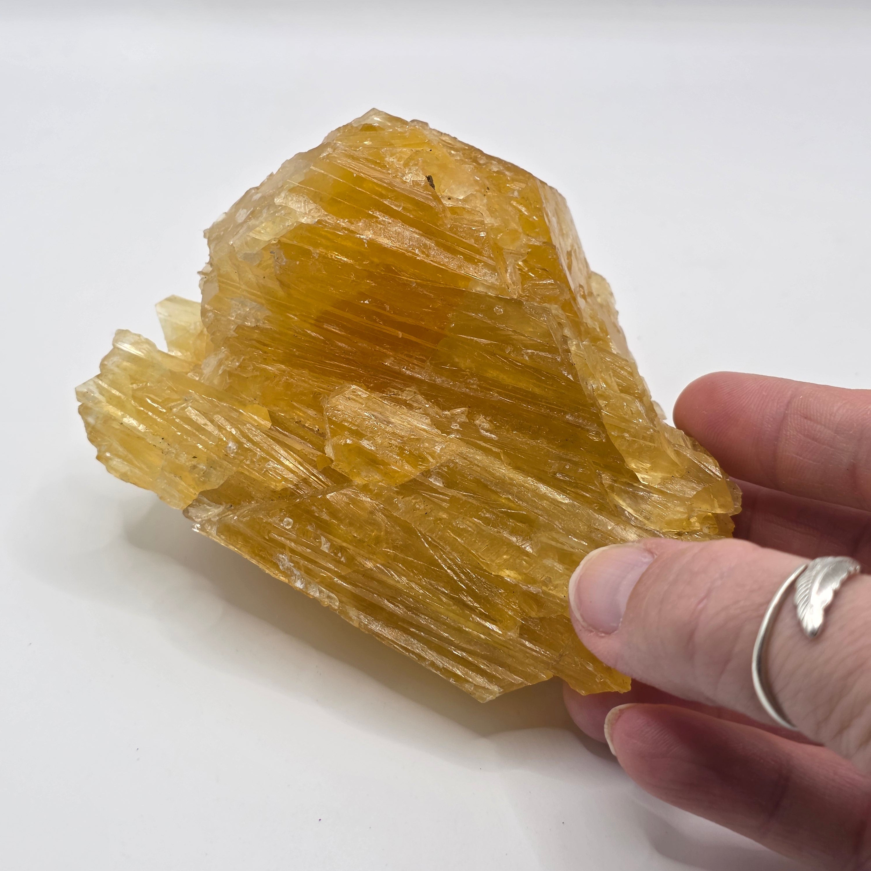Golden calcite 470g held in a person's hand – natural raw crystal for energy cleansing and prosperity