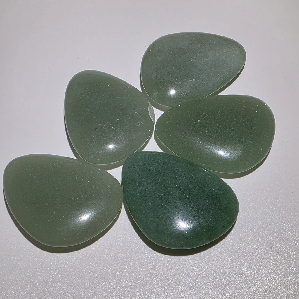 angled view of 5 green aventurine palm stones on a white background