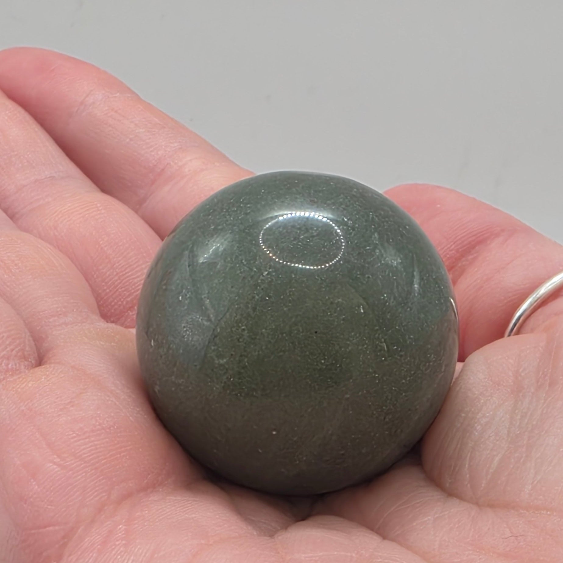 Green aventurine sphere 35mm held in a person's hand – smooth polished crystal for luck and abundance