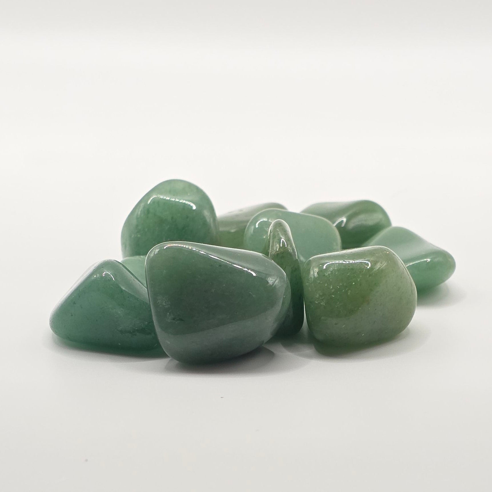 Flurry of Green aventurine tumbled stones on white background – dark green crystal for luck and opportunity