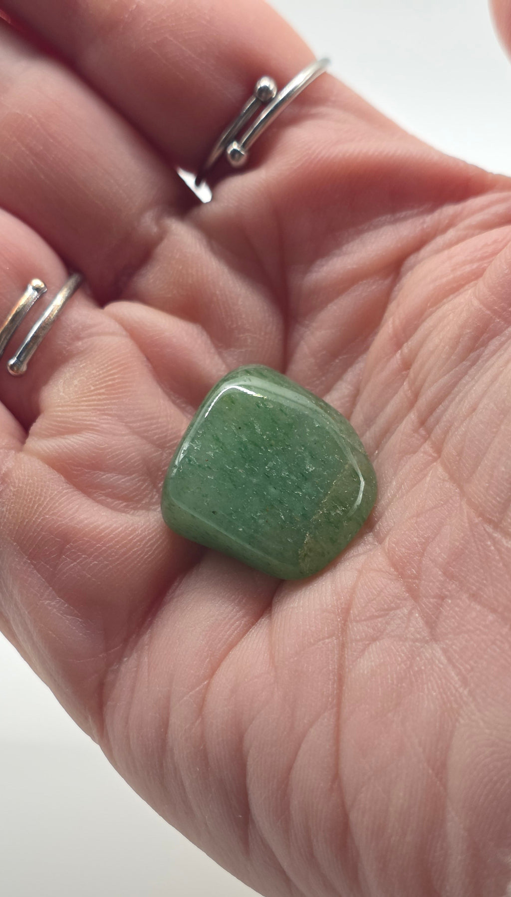 Green aventurine tumbled stone in palm on white background – dark green crystal for luck and opportunity