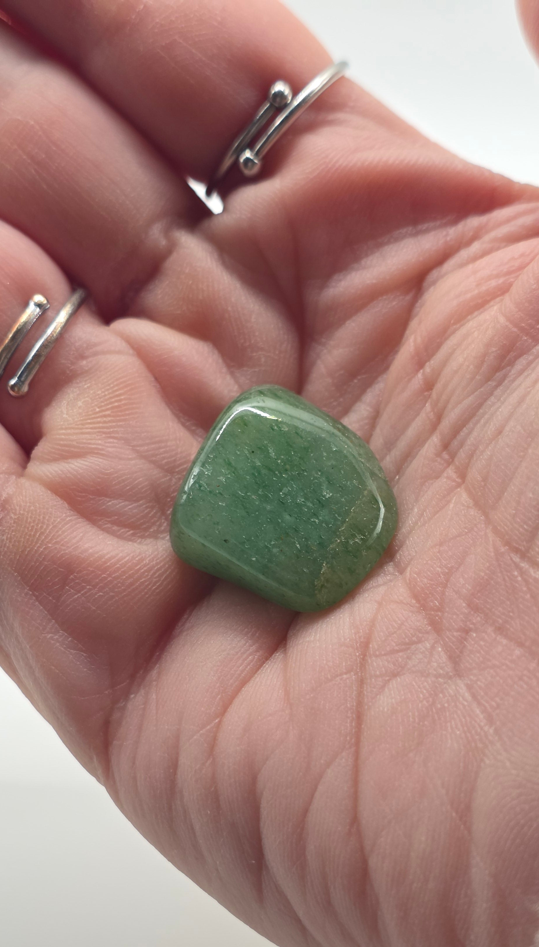 Green aventurine tumbled stone in palm on white background – dark green crystal for luck and opportunity