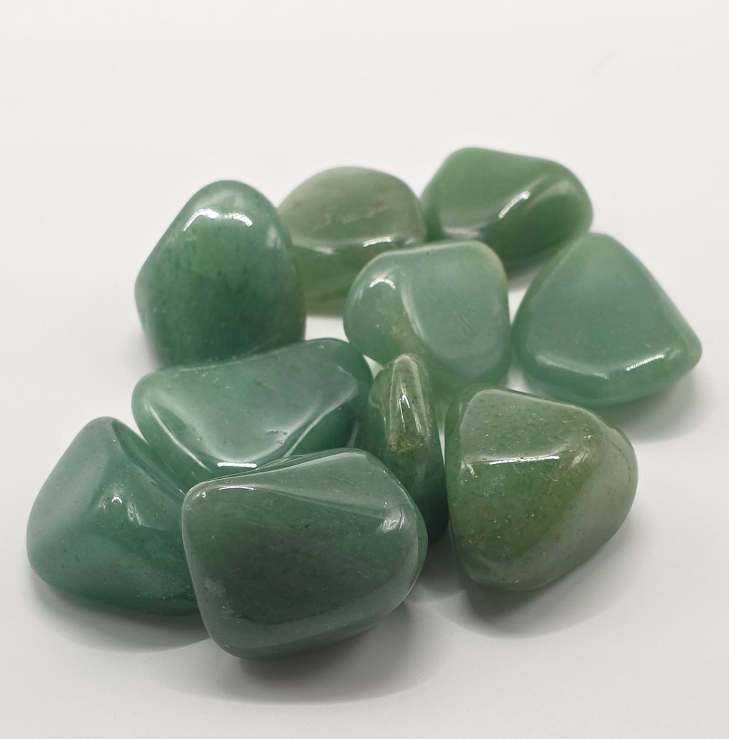 Overhead shot of Green aventurine tumbled stones on white background – dark green crystal for luck and opportunity