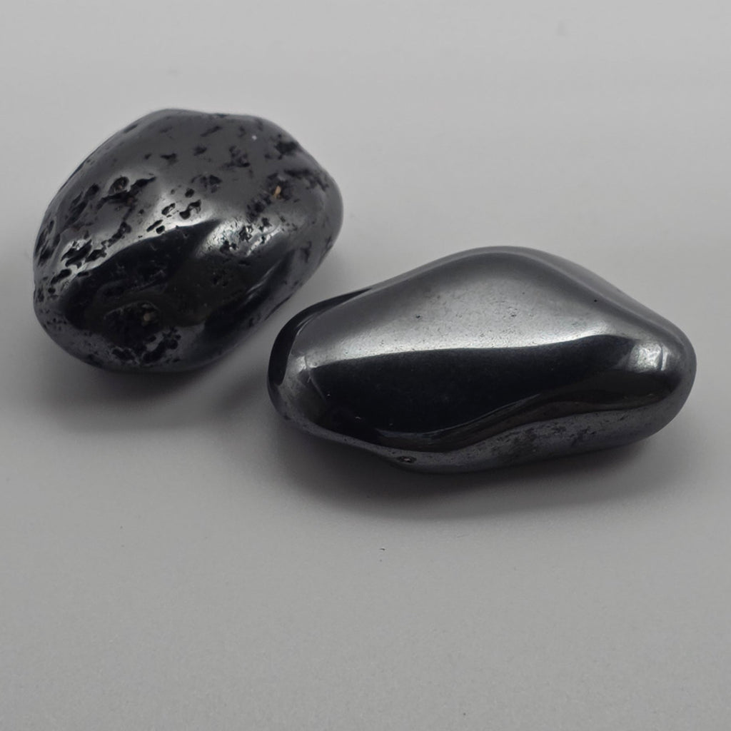 2 Hematite tumbled stones on white background – metallic grey-black crystal for grounding, focus and protection