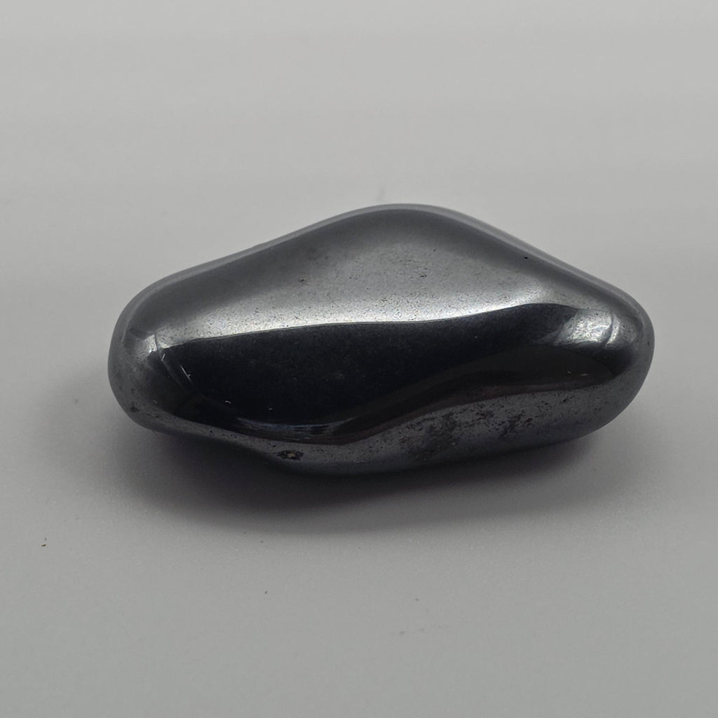 Hematite tumbled stone on white background – metallic grey-black crystal for grounding, focus and protection