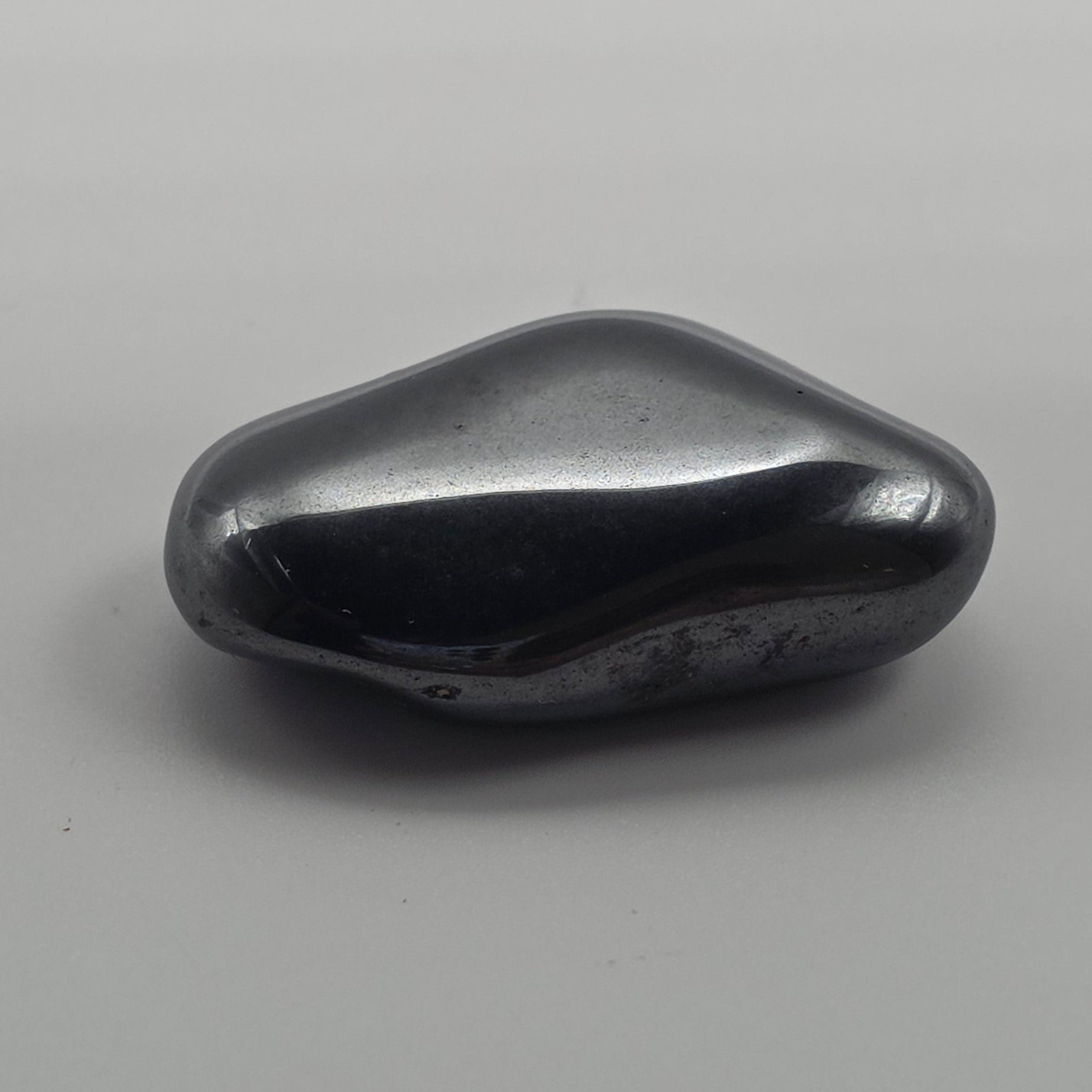 Hematite tumbled stone on white background – metallic grey-black crystal for grounding, focus and protection