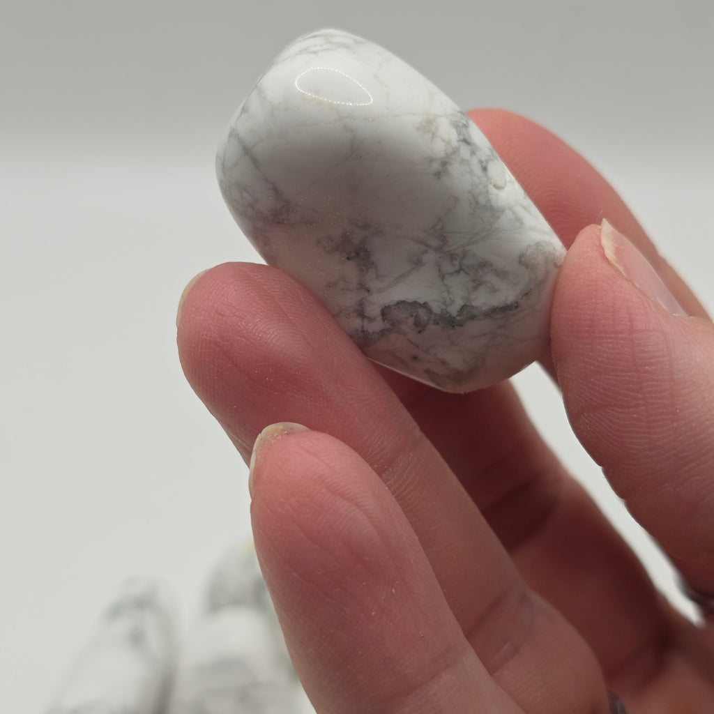 Howlite tumbled stone from South Africa held in a person's hand – smooth polished crystal for stress relief
