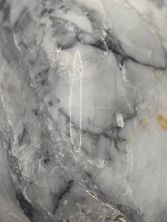 Close up of South African howlite tumbled stone showing distinctive grey veining patterns on white stone