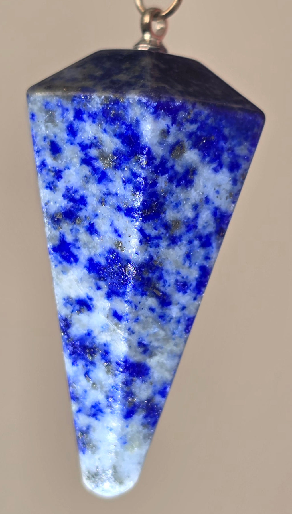 Close up of faceted lapis lazuli crystal point showing deep blue colour and natural pyrite flecks