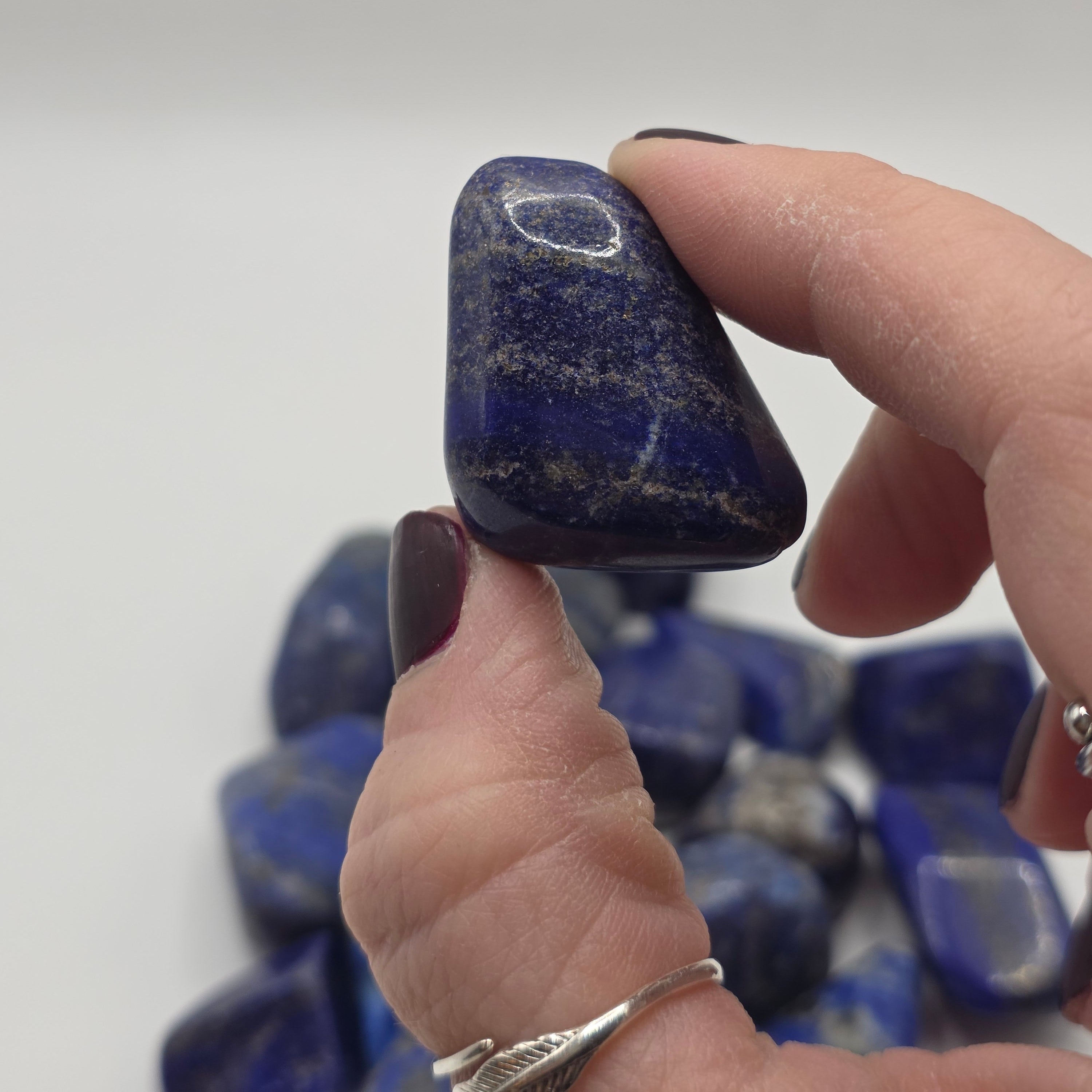 Lapis lazuli tumbled stone held in a person's hand – smooth polished crystal for throat and third eye chakra healing