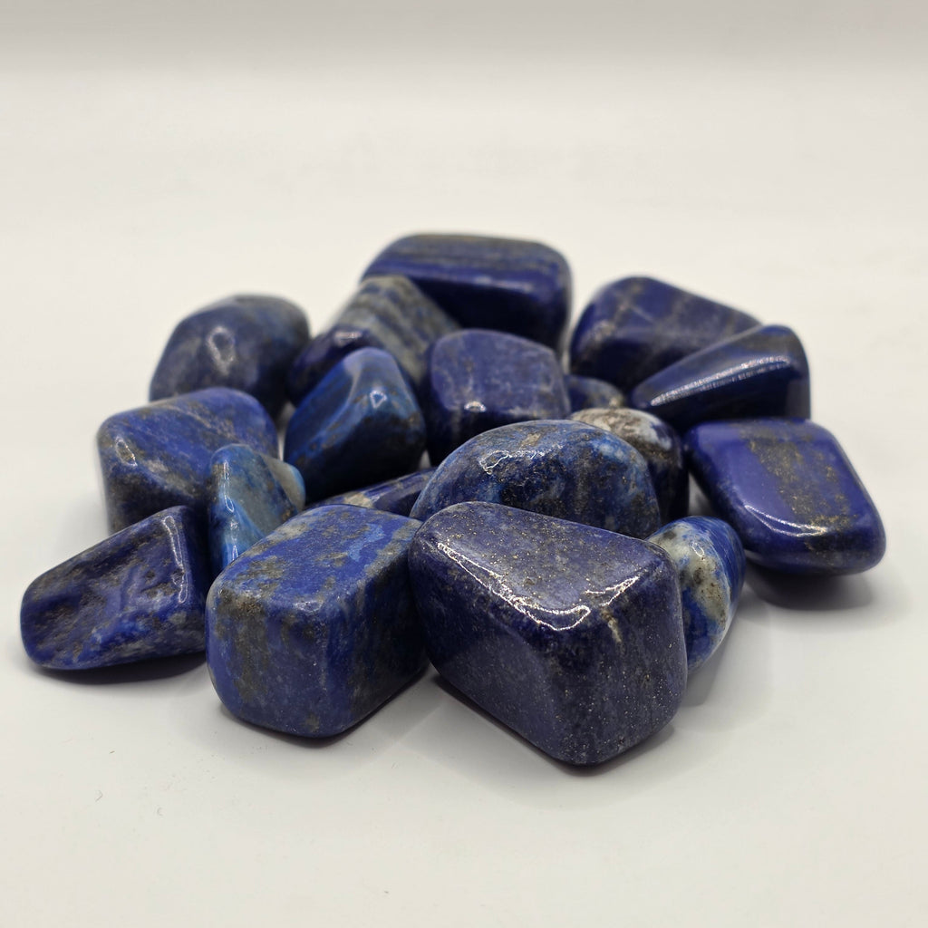 Group of lapis lazuli tumbled stones showing natural variation in blue colour and pyrite distribution