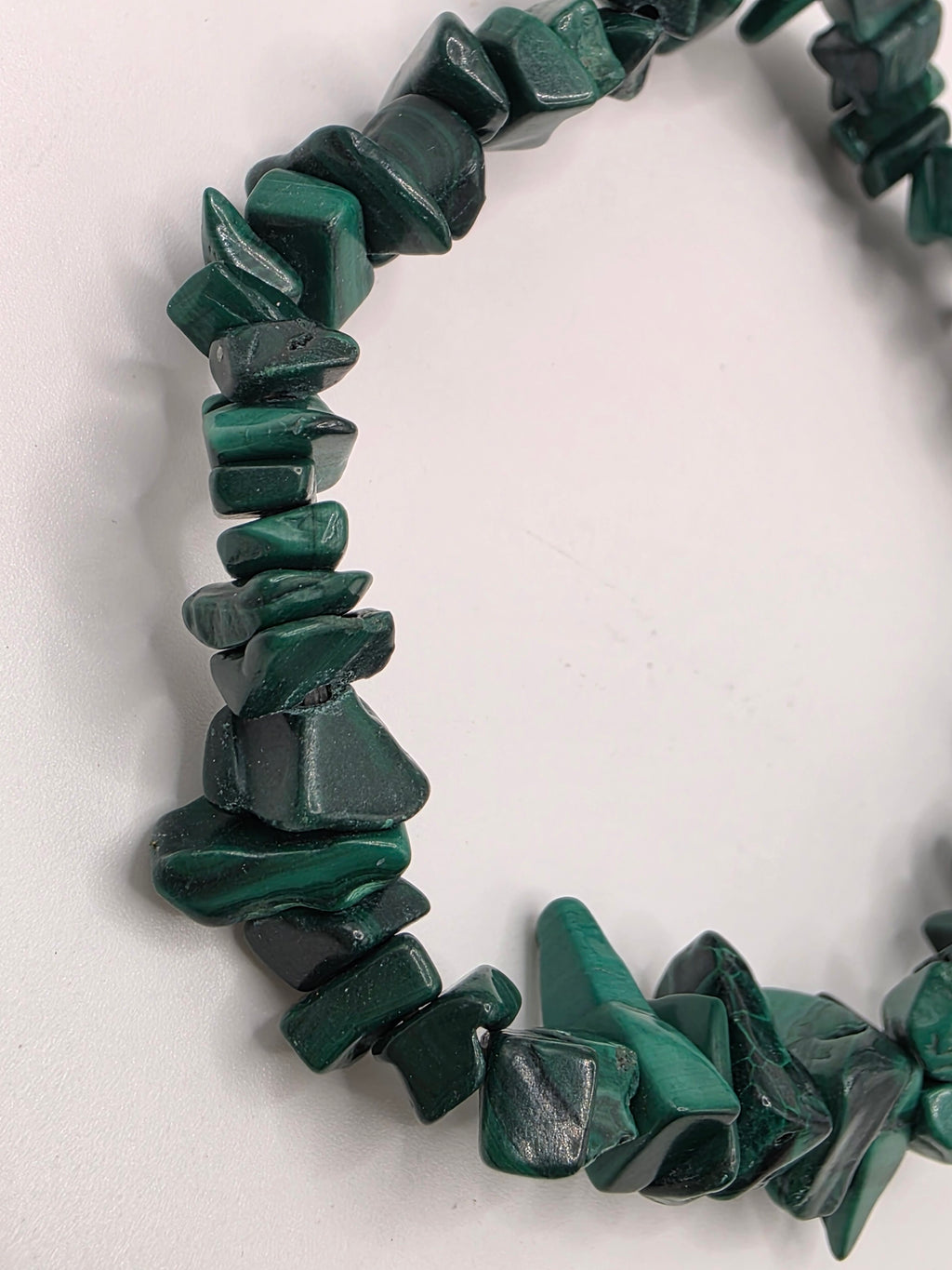 Close up of malachite chips showing rich green colour, natural banding, and swirl patterns