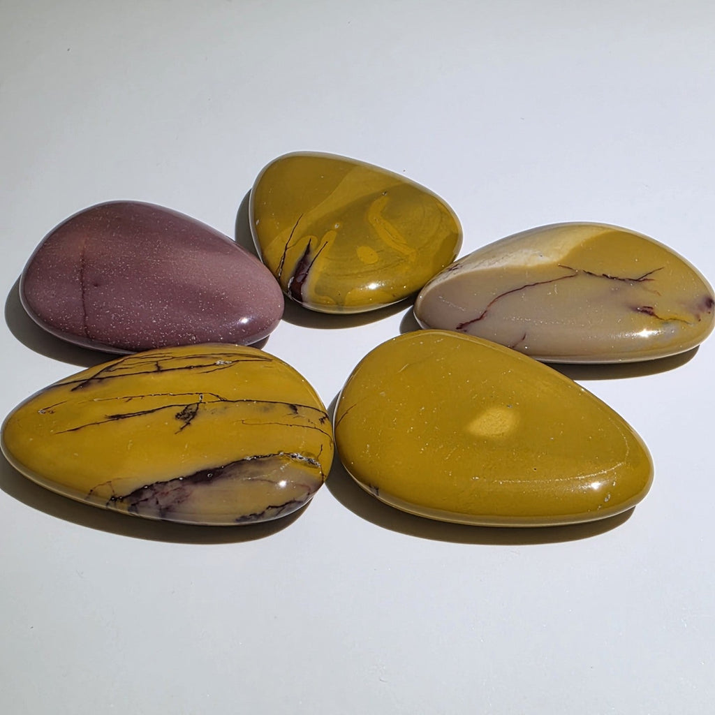 Side view of mookaite palm stone showing polished edge and natural colour layering