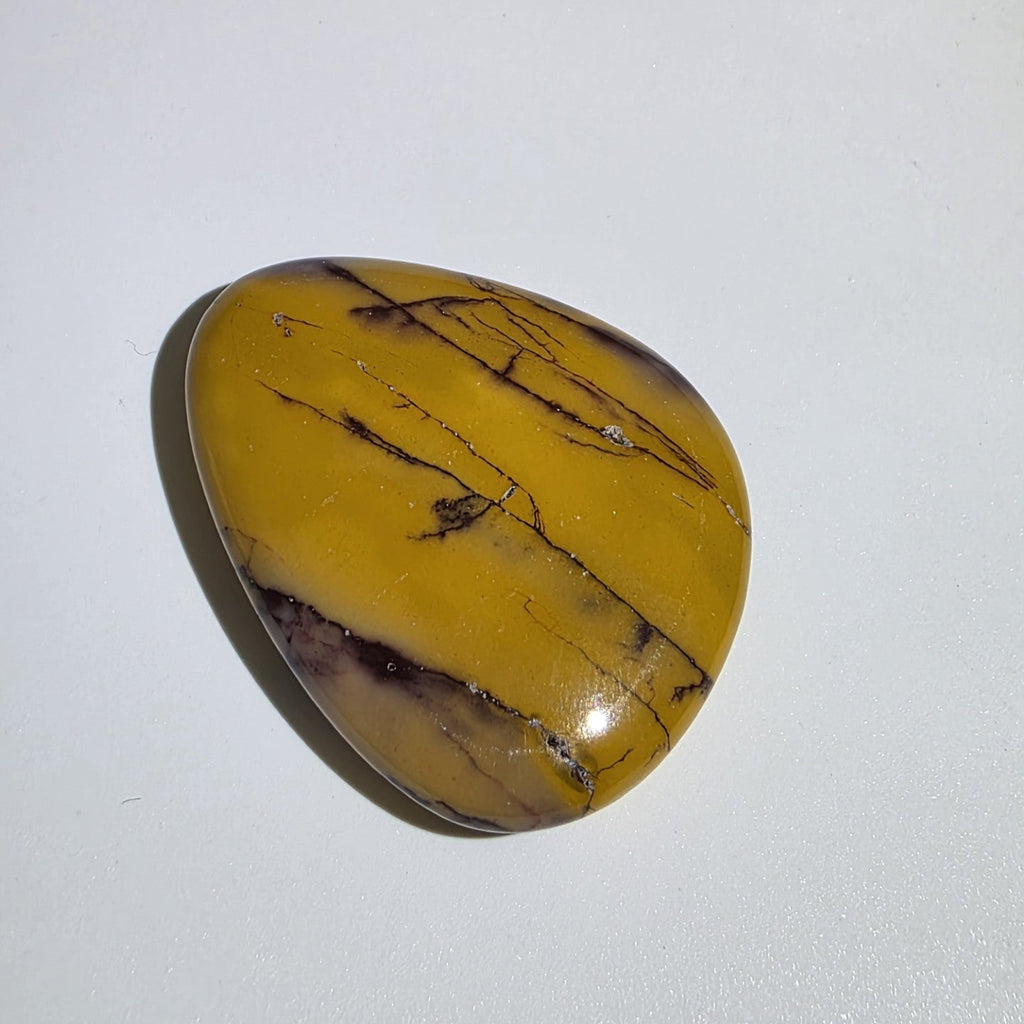 Mookaite palm stone on white background – natural Australian jasper in rich earthy tones of burgundy, cream, and yellow