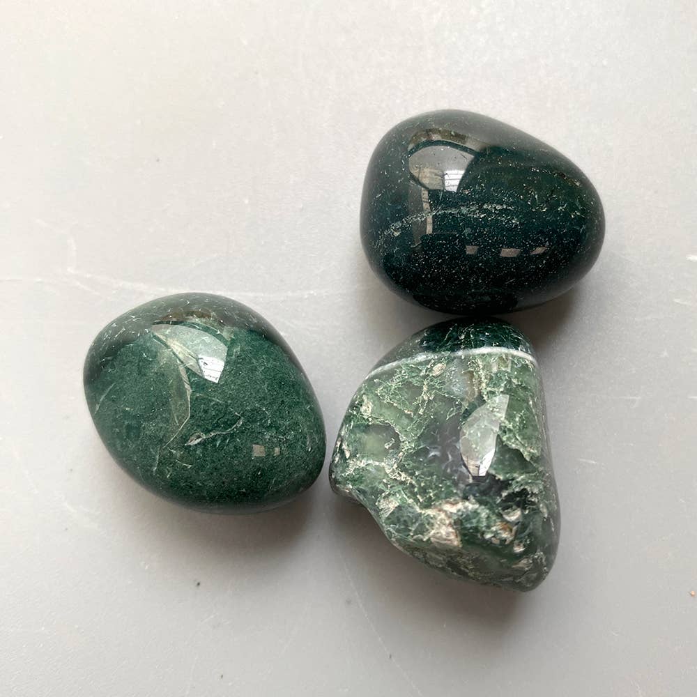 Group of moss agate tumbled stones showing natural variation in green inclusions and patterns