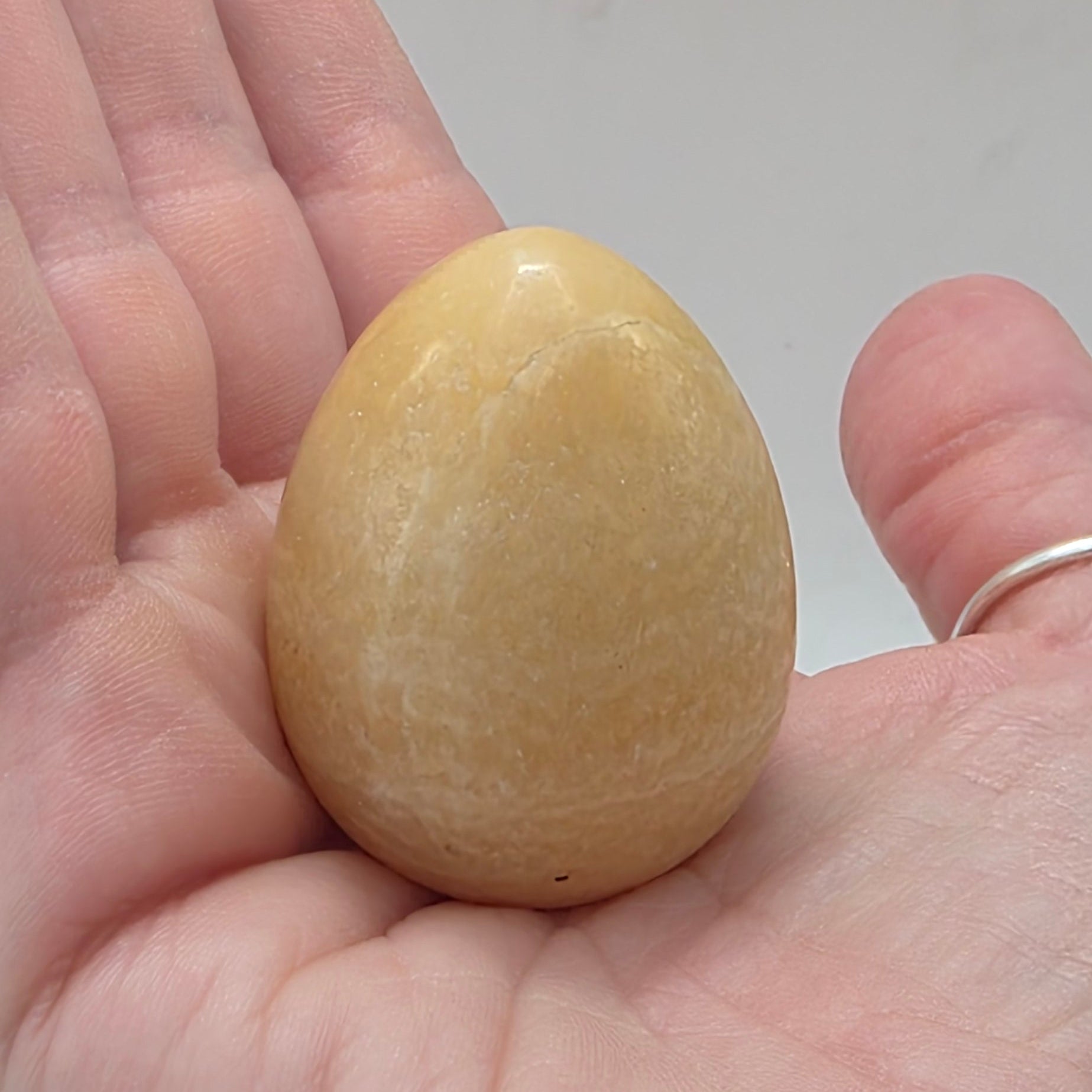 Orange calcite egg 45mm held in a person's hand – smooth crystal egg for sacral chakra energy