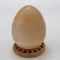 Orange calcite crystal egg 45mm on white background – polished stone egg for creativity and vitality