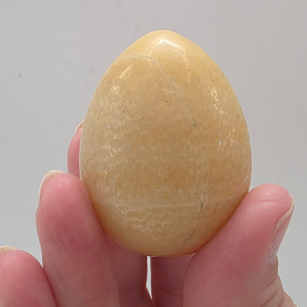 Close up of orange calcite egg showing polished finish and vibrant orange colour